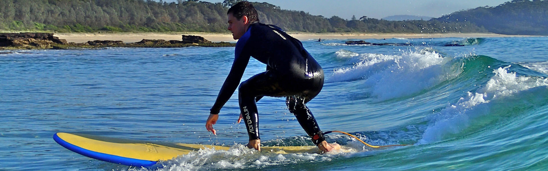 Man in wetsuit on surfboard riding a wave