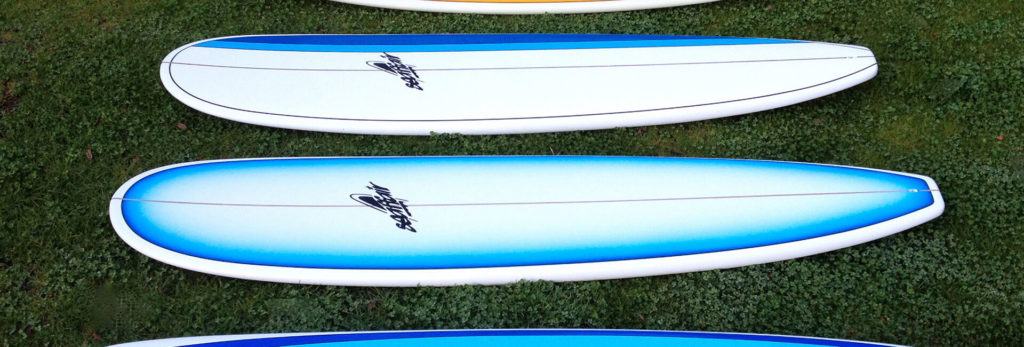 Surfboard hire Blue coloured surfboards side by side laying on grass