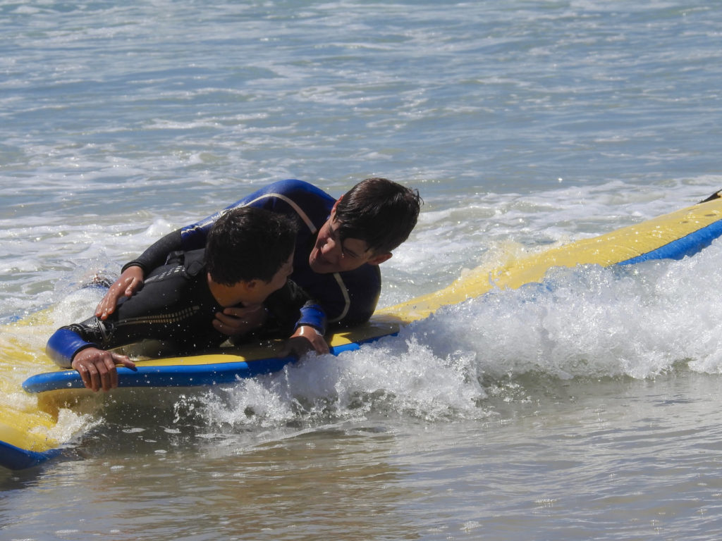 participants of the surf lessons and water safety course bring a victim to shore