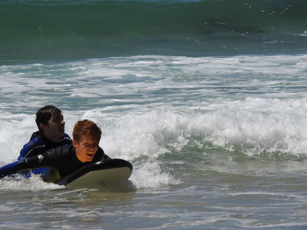 participants of the surf lessons and water safety course bring a victim to shore