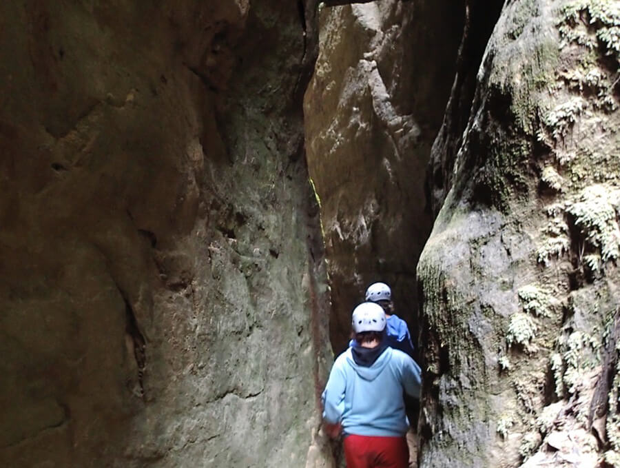 Two people with helmets walking through cave