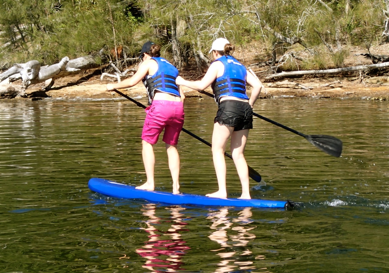 picture of two women sharing a stand up paddle board
