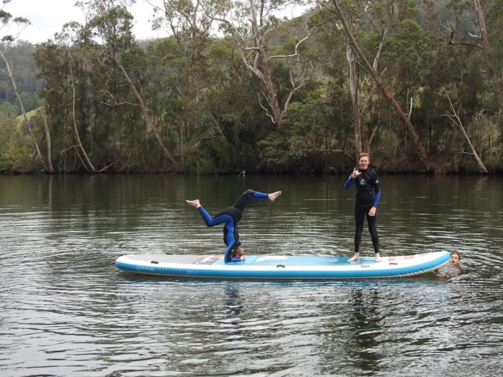 Two people on monster paddle board with one in handstand type pose